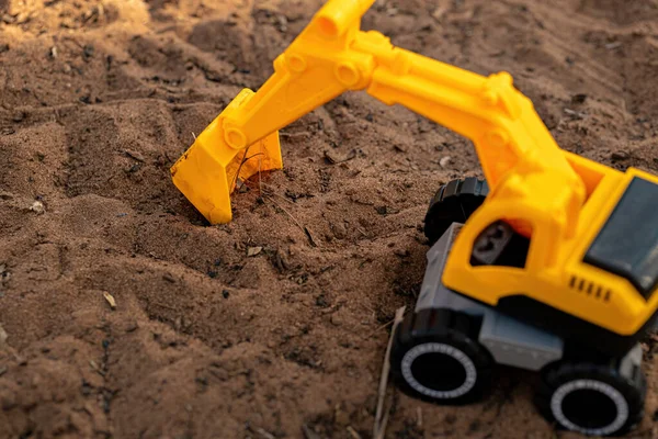 選択的な焦点で地面に黄色と黒の色のおもちゃの掘削機ミニチュア — ストック写真