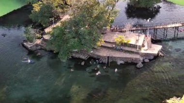 Lagoa Santa, Goias, Brezilya - 05 05 2024 İHA yörüngesi telefoto ile göl kenarındaki kayalık bir ada etrafında turistler yüzerken görülüyor..