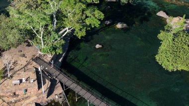 Lagoa Santa, Goias, Brezilya - 07 05 2024. Drone 'un hava fotoğrafı, temiz termal lagünün üzerindeki ahşap köprü yapısını gösteriyor. Aşağıda kayalar ve su ortamını gösteriyor..