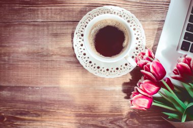 kahve fincanı, dizüstü bilgisayar ve ahşap masaya çiçek. Vintage etkisi.