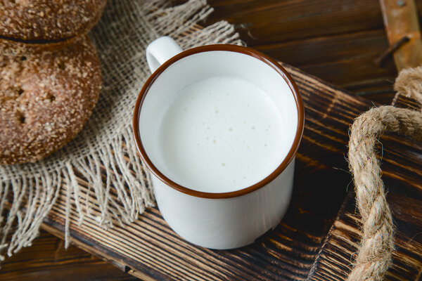 cup of warm milk and bread on a wooden background