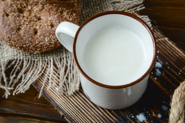 Cangkir susu hangat dan roti pada latar belakang kayu — Stok Foto