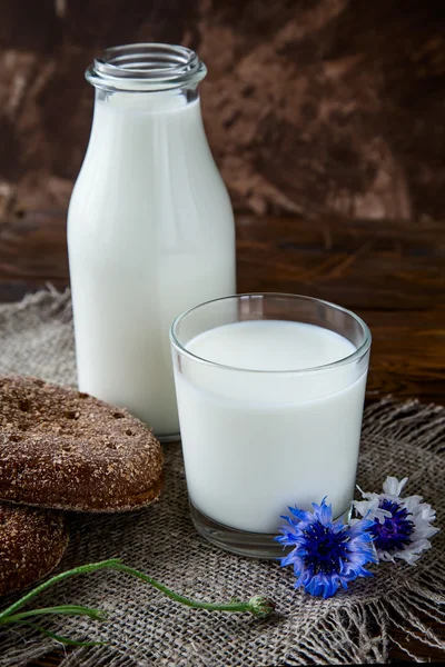 Fles met melk en glas melk aan houten tafel. — Stockfoto