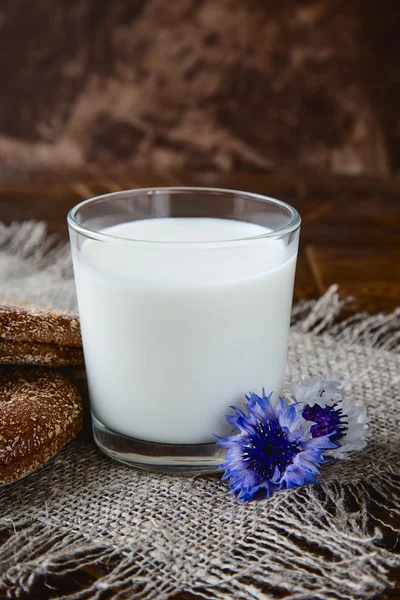 Glas melk aan houten tafel met mooie bloemen — Stockfoto