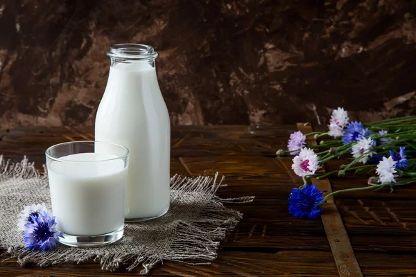 Fles met melk en glas melk aan houten tafel. — Stockfoto