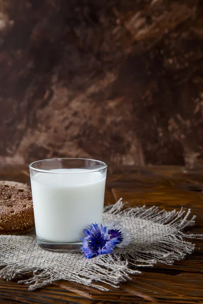Glas melk aan houten tafel met mooie bloemen — Stockfoto