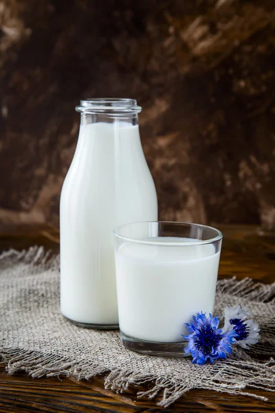 Fles met melk en glas melk aan houten tafel. — Stockfoto