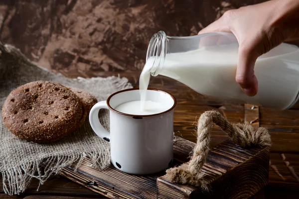 Hand gieten melk uit een fles in een kopje — Stockfoto