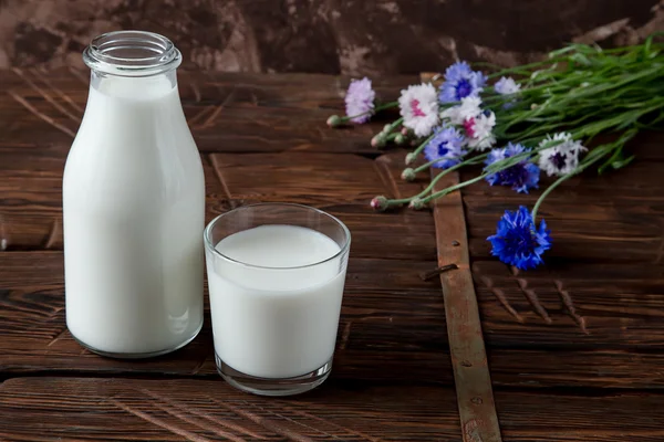 Fles met melk en glas melk aan houten tafel. — Stockfoto