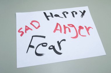 İnsan duygularını keşfederek mutluluk öfke ve korku zihinsel sağlık farkındalığı ve duygusal refah kavramları için kağıda elle yazılmış.