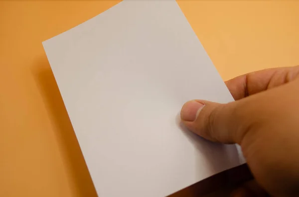 Sıcak turuncu arka plana karşı notlar ya da mesajlar için boş kağıt kartı tutmak tasarım modelleri ve davetiyeler için mükemmel.