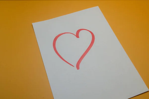 Beyaz kart üzerine el çizilmiş kalp canlı sarı arka plana karşı sevgi, şefkat ve yürekten bir duygu yaratır.