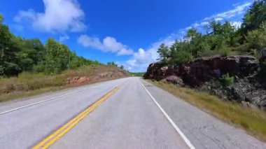 6. Otoyol 'da sahne sürüşü. Rocky Doğa Dağı manzarası ileri sürüş plakası. Yazın Yeşil Orman ve Kanada Kalkanı. Manitoulin Adası, Ontario, Kanada 'da asfalt yolda POV kullanıyor..