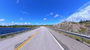 6. Otoyol 'da sahne sürüşü. Rocky Doğa Dağı manzarası ileri sürüş plakası. Yazın Yeşil Orman ve Kanada Kalkanı. Manitoulin Adası, Ontario, Kanada 'da asfalt yolda POV kullanıyor..