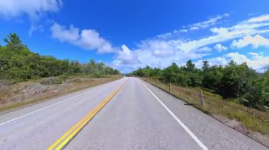 6. Otoyol 'da sahne sürüşü. Rocky Doğa Dağı manzarası ileri sürüş plakası. Yazın Yeşil Orman ve Kanada Kalkanı. Manitoulin Adası, Ontario, Kanada 'da asfalt yolda POV kullanıyor..