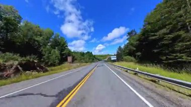 6. Otoyol 'da sahne sürüşü. Rocky Doğa Dağı manzarası ileri sürüş plakası. Yazın Yeşil Orman ve Kanada Kalkanı. Manitoulin Adası, Ontario, Kanada 'da asfalt yolda POV kullanıyor..