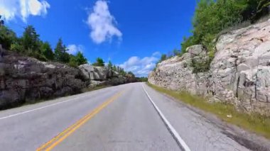 6. Otoyol 'da sahne sürüşü. Rocky Doğa Dağı manzarası ileri sürüş plakası. Yazın Yeşil Orman ve Kanada Kalkanı. Manitoulin Adası, Ontario, Kanada 'da asfalt yolda POV kullanıyor..