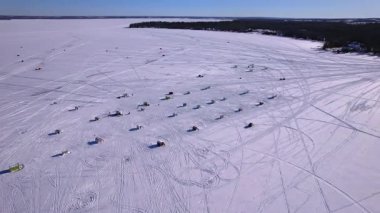 Gün batımında Ontario Kanada 'da bulunan Simcoe Gölü' ndeki kar motosikletli yarış pistinin üzerinde uçan karmaşık bir şablon. Buz balıkçılığı için balıkçı kulübeleri olan kış manzarası. Kış sporları.