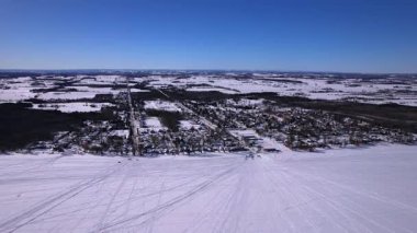 Kar araçlarının hava aracı görüntüleri, parlak güneşli güneş ışığı altında taze kış karının üzerindeki kavisli rayların desenlerini belirler. Donmuş Simcoe Gölü, Cooks Körfezi, Innisfil, Kanada 'da buzda balık tutma sporu.