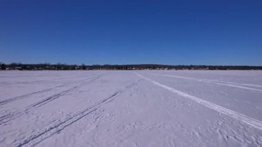 Innisfil, Ontario 'daki Cooks Körfezi' ndeki Simcoe Gölü 'nün donmuş sularında kar arabası ya da kar köpeği izlerindeki insansız hava aracı görüntüleri. Jumbo tünek, turna balığı, beyaz balık için kış balıkçılığı sezonu kiralamaları.