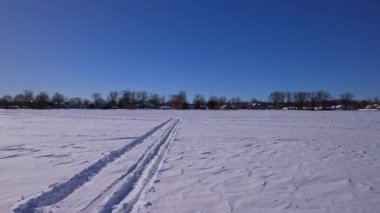 Kar motosikleti, ATV ya da buzda balık avlama kızağı ve karlı göl Simcoe boyunca kar köpeği pistlerinde insansız hava aracı görüntüsü. Turistler ve buz balıkçılığı sezonunda kış tatili. Mavi gökyüzü.