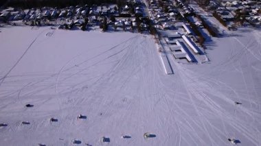 Kar araçları, atv ve buzda balık avlama kızakları ya da güneşli bir kış gününde taze kar yüzeyini gösteren kızak izleri karmaşık çizgiler ve gölge dokusu desenleri yaratıyor. Donmuş göl karlı manzara.