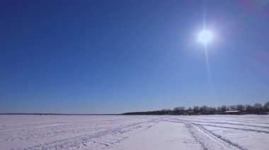 Kar motosikleti, ATV ya da buzda balık avlama kızağı ve karlı göl Simcoe boyunca kar köpeği pistlerinde insansız hava aracı görüntüsü. Turistler ve buz balıkçılığı sezonunda kış tatili. Mavi gökyüzü.