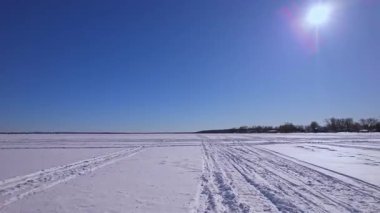 Kar motosikleti, ATV ya da buzda balık avlama kızağı ve karlı göl Simcoe boyunca kar köpeği pistlerinden oluşan POV sürücü plakası. Turistler ve buz balıkçılığı sezonunda kış tatili. Mavi gökyüzü.