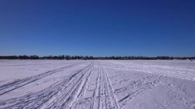 Kar motosikleti, ATV ya da buzda balık avlama kızağı ve karlı göl Simcoe boyunca kar köpeği pistlerinden oluşan POV sürücü plakası. Turistler ve buz balıkçılığı sezonunda kış tatili. Mavi gökyüzü.