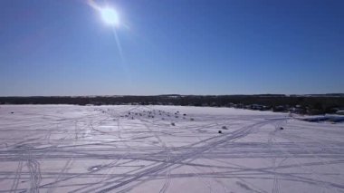 Gün batımında Ontario Kanada 'da bulunan Simcoe Gölü' ndeki kar motosikletli yarış pistinin üzerinde uçan karmaşık bir şablon. Buz balıkçılığı için balıkçı kulübeleri olan kış manzarası. Kış sporları.