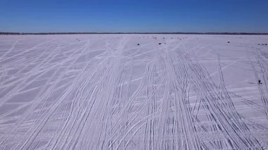 Donmuş göl ve kar üzerinde kızak ya da kızak izlerinin hava görüntüsü. Güneşli bir kış gününde taze kar yüzeyini gösteren kayak ve buz kızağı ya da dişli kızak izleri..