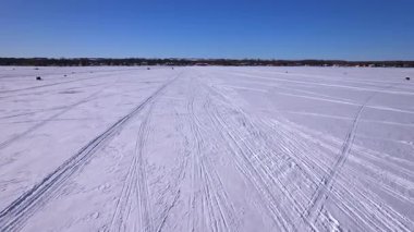 Donmuş göl ve kar üzerinde kızak ya da kızak izlerinin hava görüntüsü. Güneşli bir kış gününde taze kar yüzeyini gösteren kayak ve buz kızağı ya da dişli kızak izleri..
