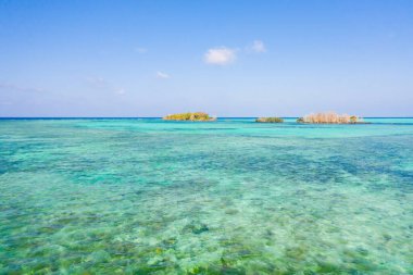 Mercan adası ve mavi deniz, yukarıdan manzara. Gündüz deniz manzarası. Turkuaz ve mavi deniz suyu. Resiflerdeki küçük adalar.