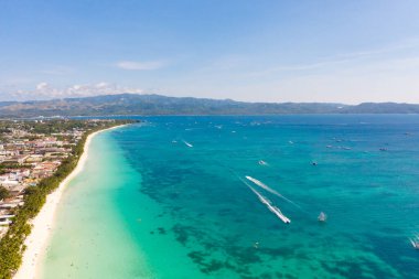Boracay Adası, Filipinler, yukarıdan manzara. Palmiye ağaçları ve tekneli turkuaz bir göl. Büyük adadaki binalar ve oteller.
