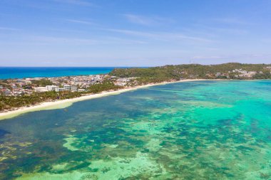 Boracay Adası, Filipinler, yukarıdan manzara. Palmiye ağaçları ve tekneli turkuaz bir göl. Büyük adadaki binalar ve oteller.