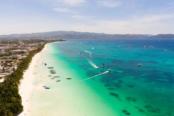 Boracay Adası, Filipinler, yukarıdan manzara. Palmiye ağaçları ve tekneli turkuaz bir göl. Büyük adadaki binalar ve oteller.