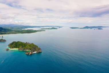 Tropikal manzara: Matukad Adası güzel plajlar ve turkuaz su manzaralı turistler. Caramoan Adaları, Filipinler. Beyaz kumlu bir plajı olan tropik bir ada..