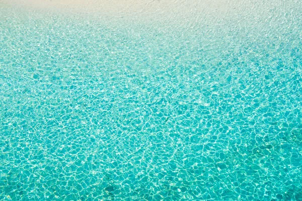 Sea surface in a turquoise lagoon, top view. The texture of sea water. Transparent turquoise sea water, natural background.