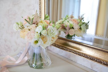 Aynanın yanında güzel bir buket çiçek. Beyaz güzel düğün buketi aynanın yanında duruyor. Ayna yansıması.