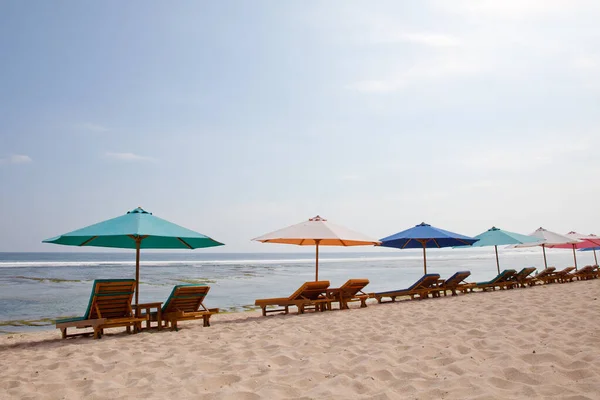海滩供游客游览 白沙滩上的日光浴者和雨伞 巴厘岛旅游胜地 印度尼西亚 阳光普照的沙滩 图库图片