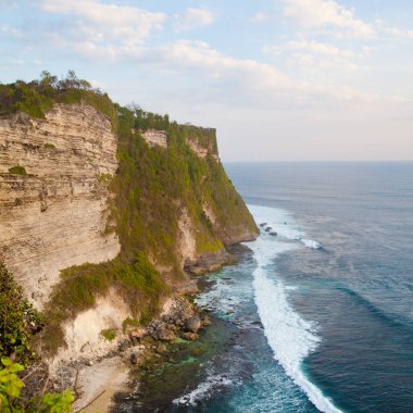Endonezya, Bali 'de mavi denizli Uluwatu uçurumunun manzarası. Kayalık uçurum ve deniz dalgaları, üst manzara.