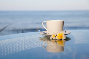 Şeffaf bir masada bir fincan kahve. Açık hava restoranındaki cam masa. Güneşli sabah