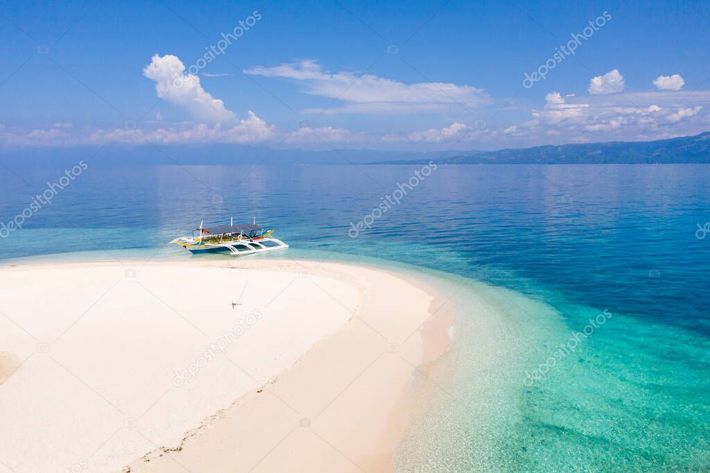 Deserted white sand beach. Seascape with tropical beach and blue sea, top view. Boat in the lagoon. Digyo Island, Philippines.
