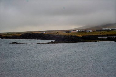 Huysuz İzlanda kıyı manzarası bulutlu gökyüzü ve kırsal evler