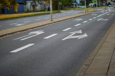 19 Ekim 2025, Varşova, Polonya: Çok şeritli bir şehir yolunun asfaltına boyanmış taze beyaz şeritli oklar, düz, sola ve sağa dönüşleri gösteriyor.