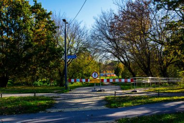 Polonya, Varşova, 2025. Kapalı park girişi, yaya levhası ve sonbahar ağaçları.
