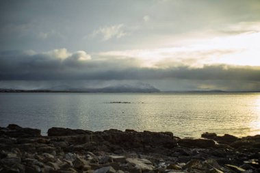 Sakin kuzey denizi bulutlu gökyüzü ve uzak karlı dağlarla