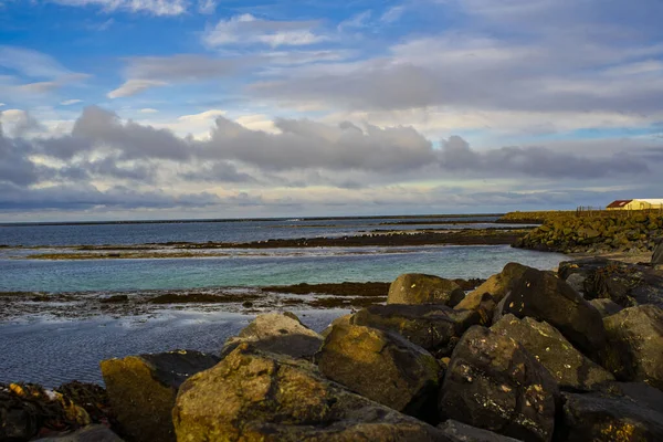 Sakin deniz ve bulutlu mavi gökyüzü ile kayalık kıyı manzarası