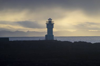 Deniz feneri silueti Denizin Üzerinde Gün Batımında
