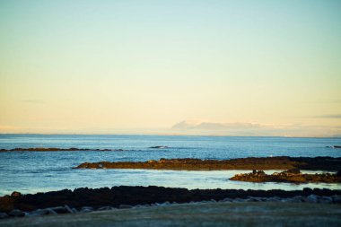 Gün doğumunda Uzak Dağlarla Sakin Kıyı Manzarası